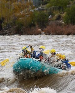 River guide and group paddling through whitewater on the Yellowstone River.