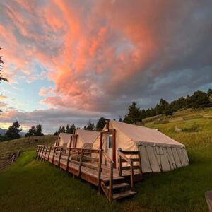 Canvas tents with pink clouds in the sky along the Yellowstone River.